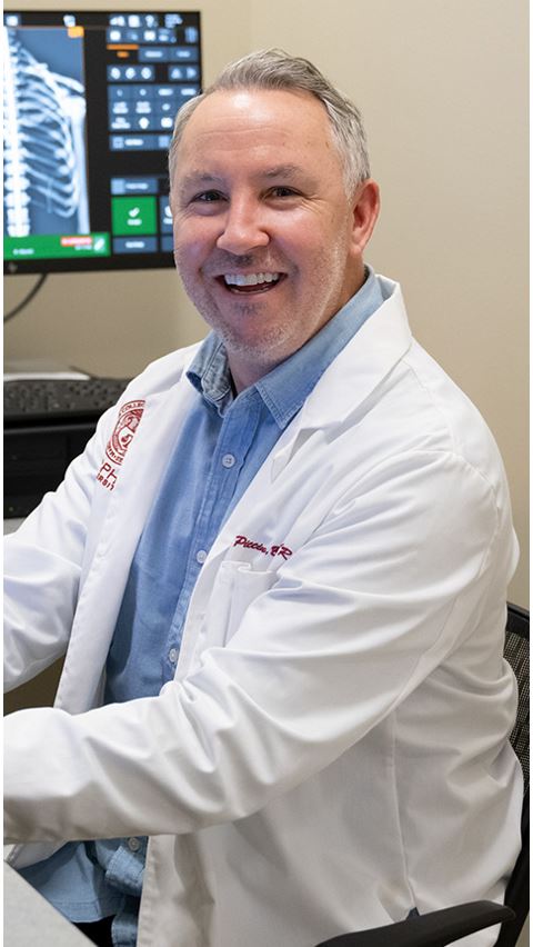 Faculty member in white coat smiling.