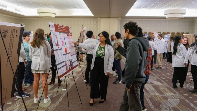 Students in a room looking at research posters