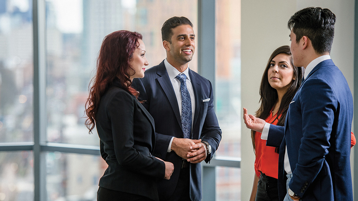 Group of three people in business attire talking. 