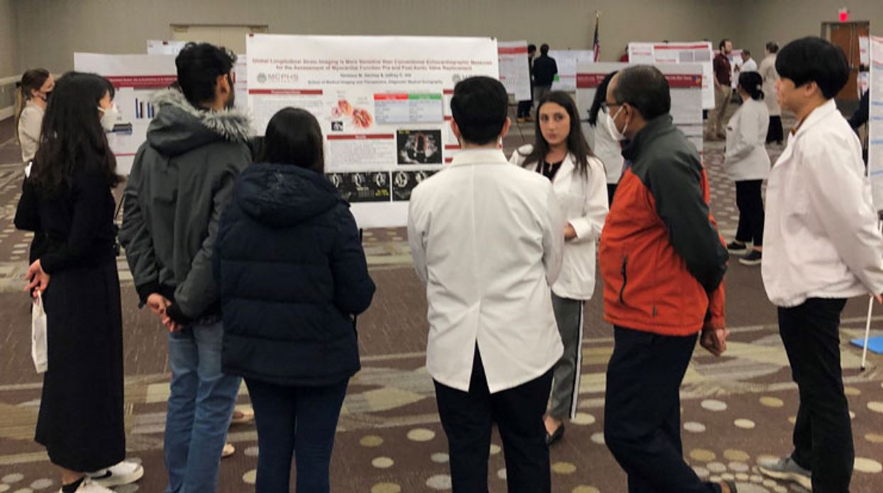 Students crowded around a poster for the student scholarship showcase